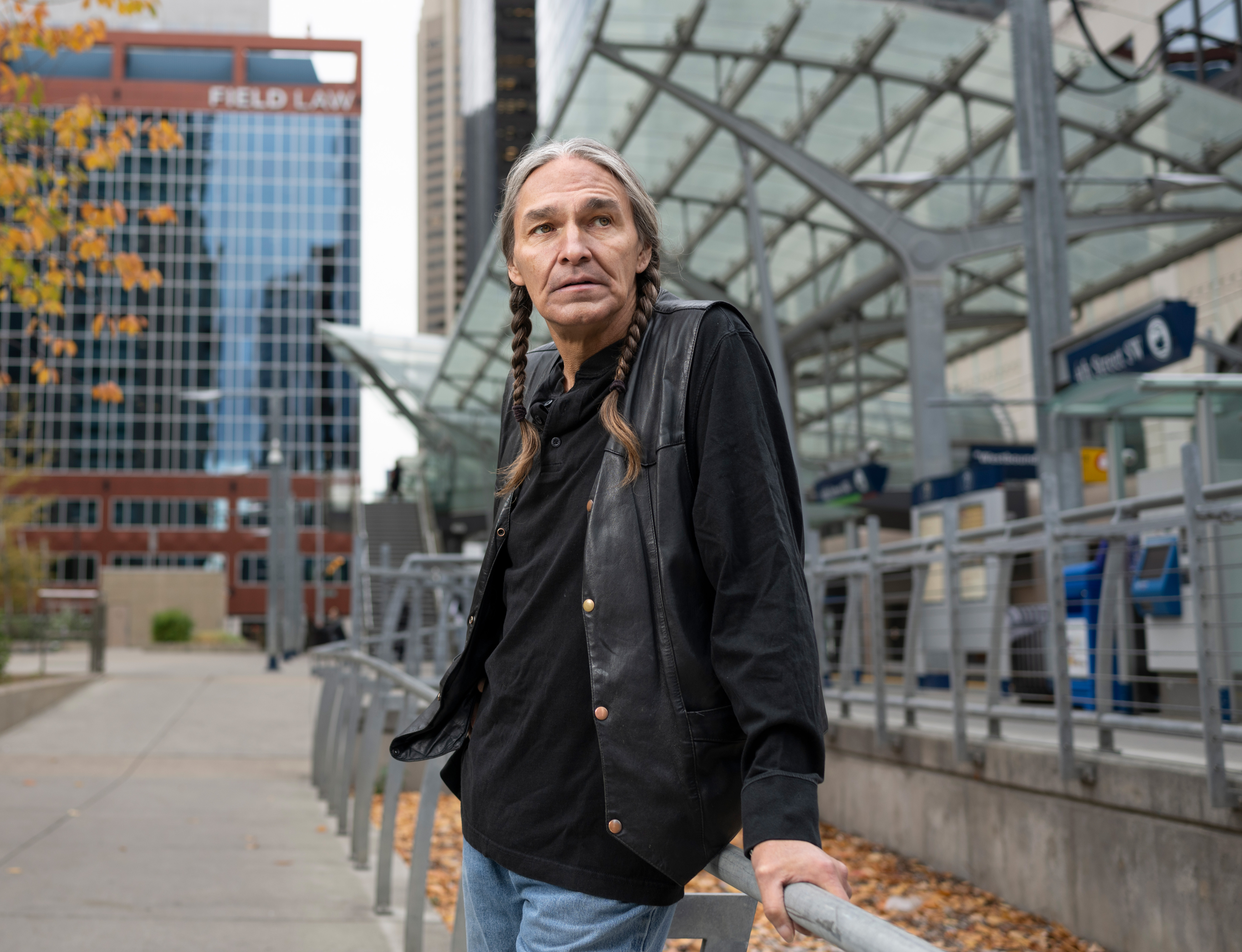 Indigenous man standing in the Calgary cityscape and leaning against a railing